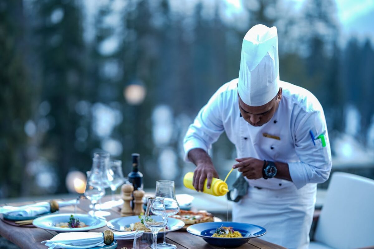 services-bg Chef expertly adds finishing touches to a gourmet dish at an outdoor restaurant setting.