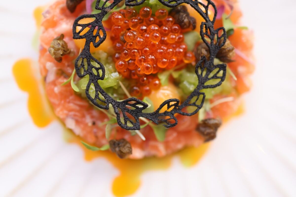 services-01 Close-up of a gourmet salmon tartare with caviar and decorative garnish on a plate.