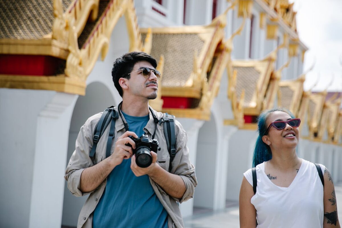 services-04 Two tourists with cameras enjoy a sunny day at an ornate Asian temple.